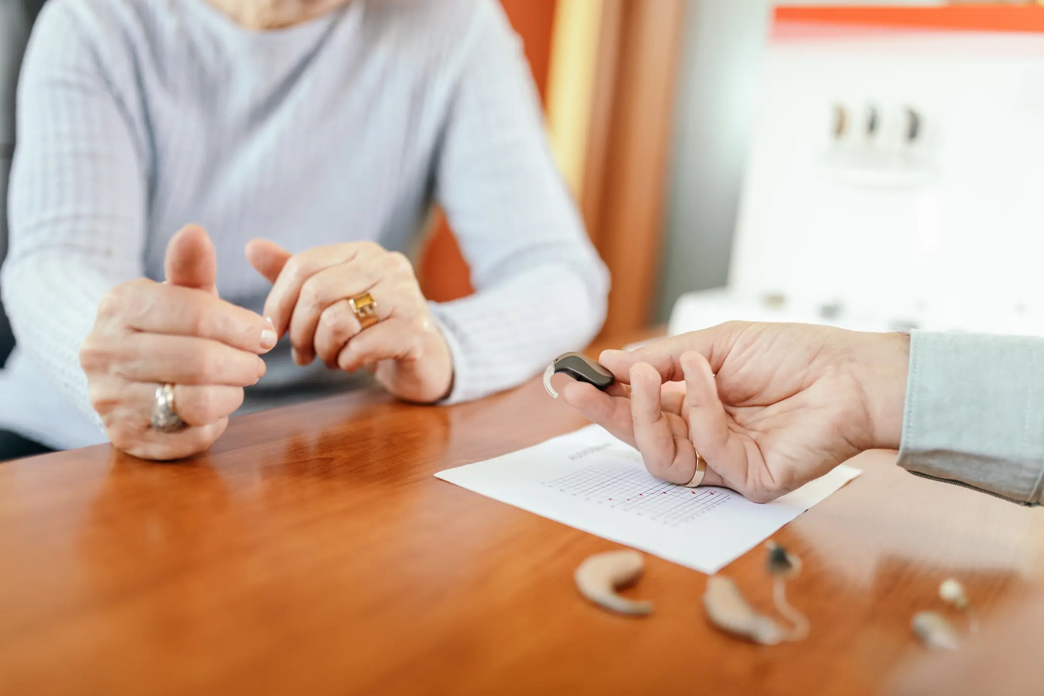 Person holding a hearing aid at a table