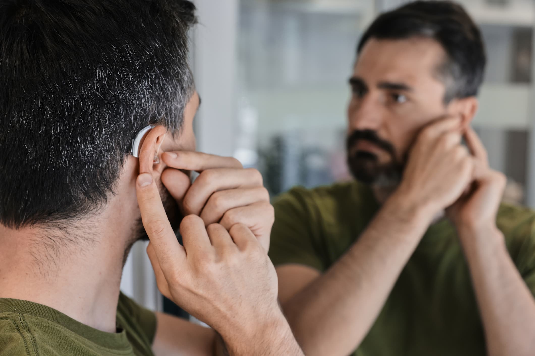 Man placing hearing aid in ear
