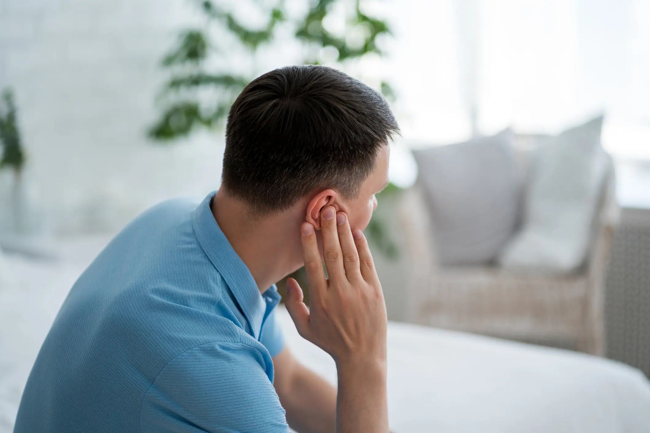 Man pressing hand against ear experiencing tinnitus