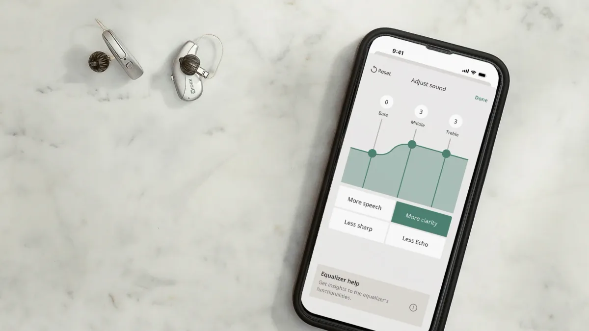 The Widex Allure app's sound customization sliders beside a pair of custom hearing aids